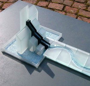 Aus einer Gebäude-Silhouette fließt Wasser in ein geschlängeltes Rinnsal.